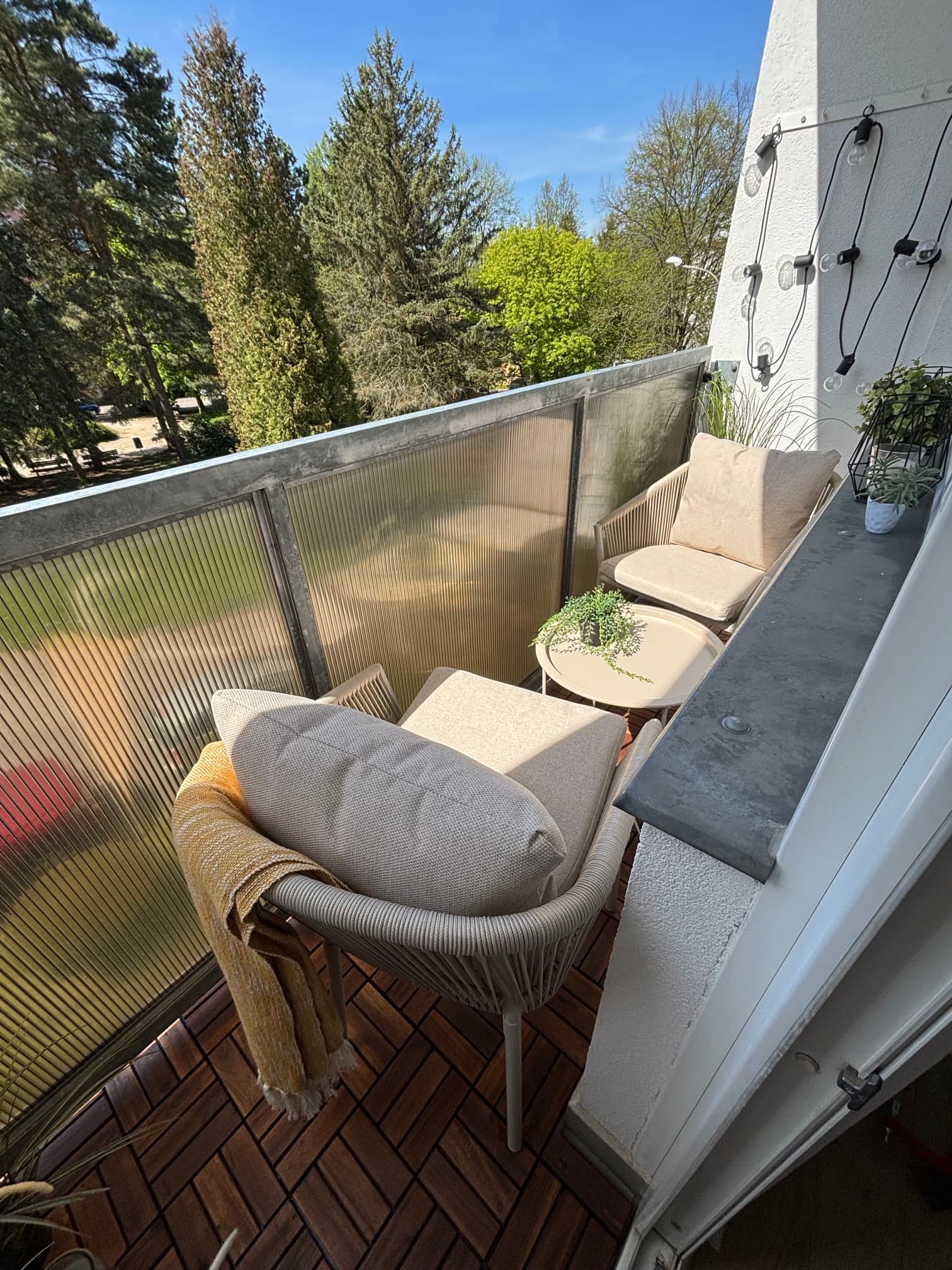 Úzký balkon s akátovou dřevěnou dlažbou a venkovním sezením